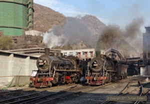 SY 1077 left the blast furnace area with loaded iron ladles while SY 1684 waited to back the replacement empty ladles under the furnaces.