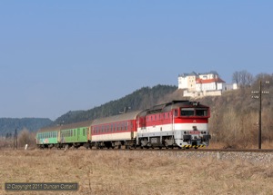 754.011 passed under the castle at Slovenska Lupka with Os7703, the 09:18 from Banska Bystrica to Brezno, on 29 March 2011.