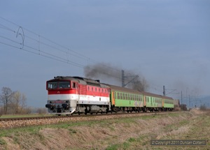 The line between Zvolen and Banska Bystrica is electrified but most trains are diesel worked. 750.273 accelerated Os7319 away from the halt at Velka Luka on 6 April 2011.