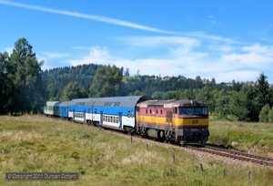 749.100 left Nove Udoli with Os8115/8114, the 11:17 stopper to Ceske Budejovice, on 11 August 2011. The buildings on the hill behind are over the border in Haidmühle, Germany.