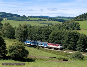 749.256 led eastbound Os8115/8114 out of a wooded cutting east of Horice na Sumave on 14 August 2011.