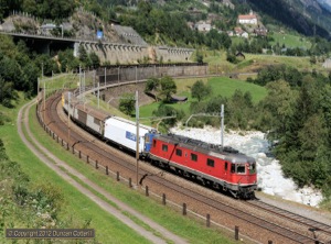 Train 50921, the 11:45 Härkingen - Cadenazzo postal rounded the Wattinger curve below Wassen behind 11629 on 29 August 2012. The vehicle behind the loco was a refrigerated van carrying dairy products from Estavayer-le-Lac.